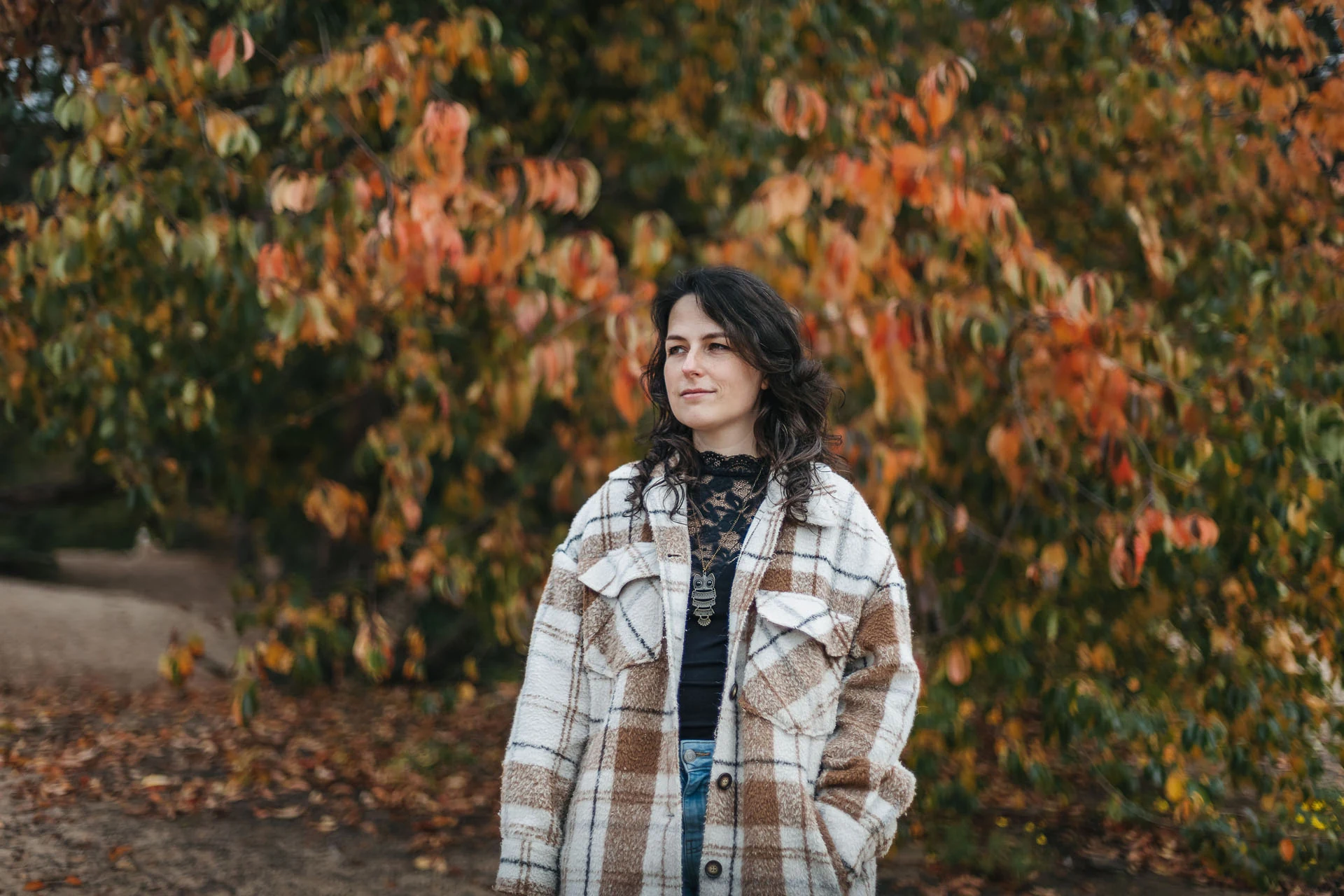 Simone Hervij in a plaid coat among autumn leaves