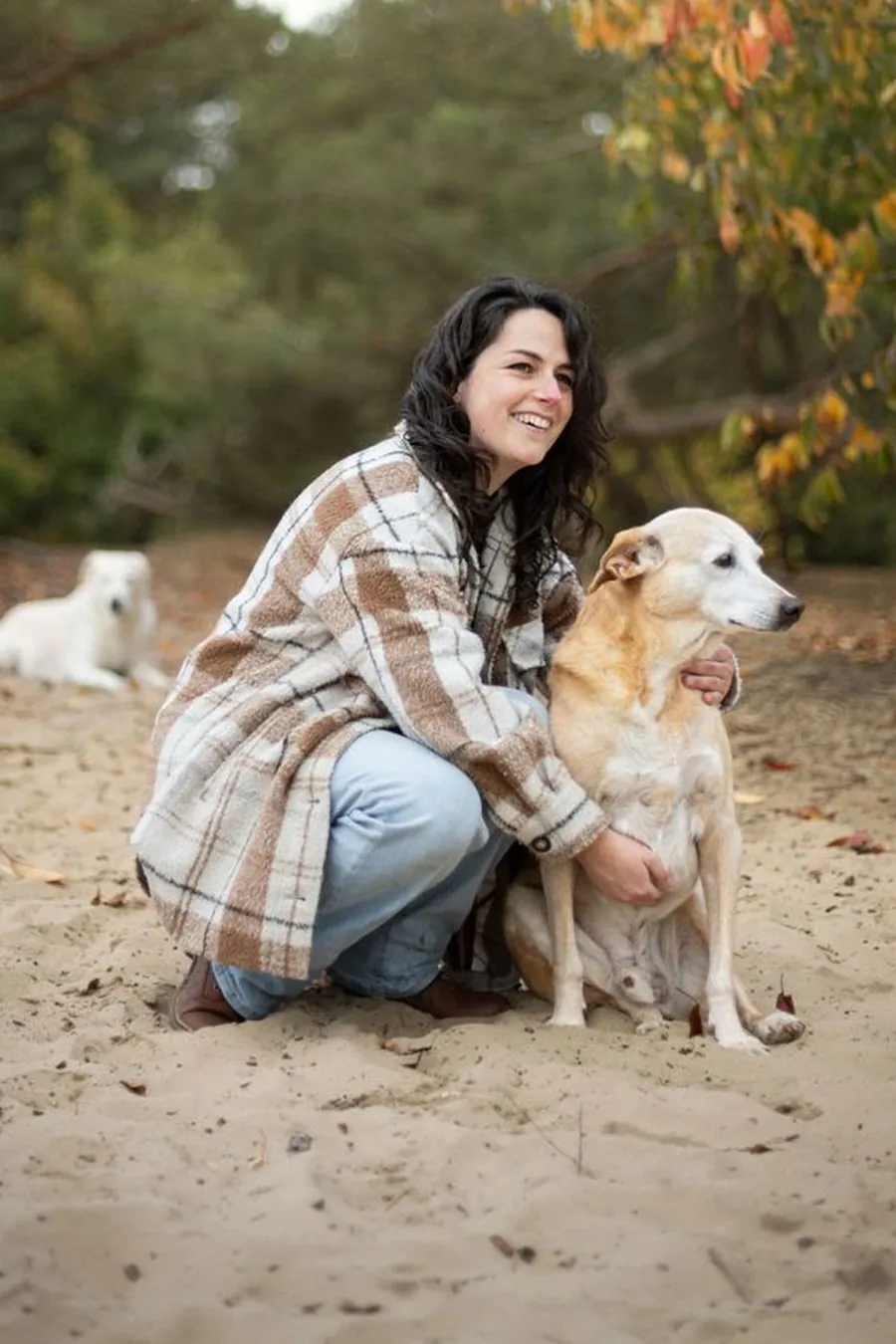 Simone Hervij kneeling in the sand, petting her dog Ted